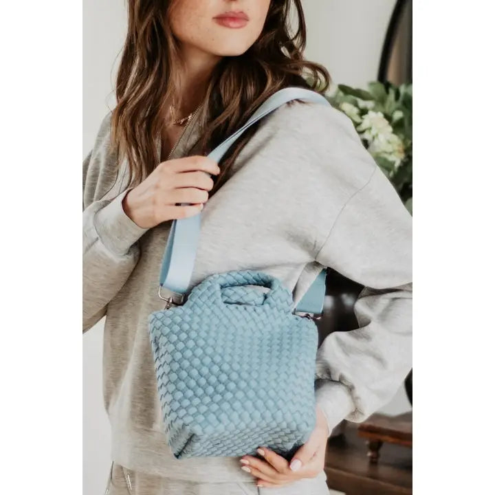 Woman holding a textured blue bag with a neutral background