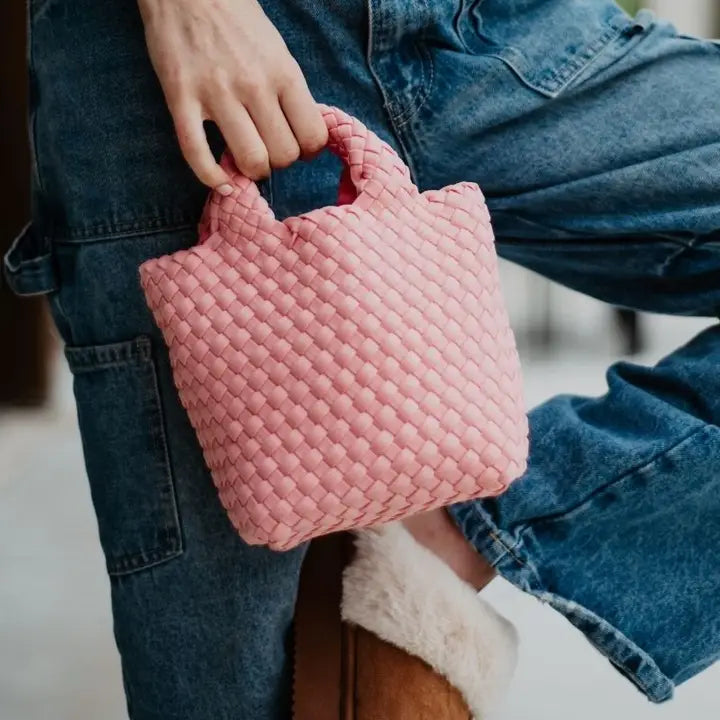 Person holding a pink textured handbag with denim jeans